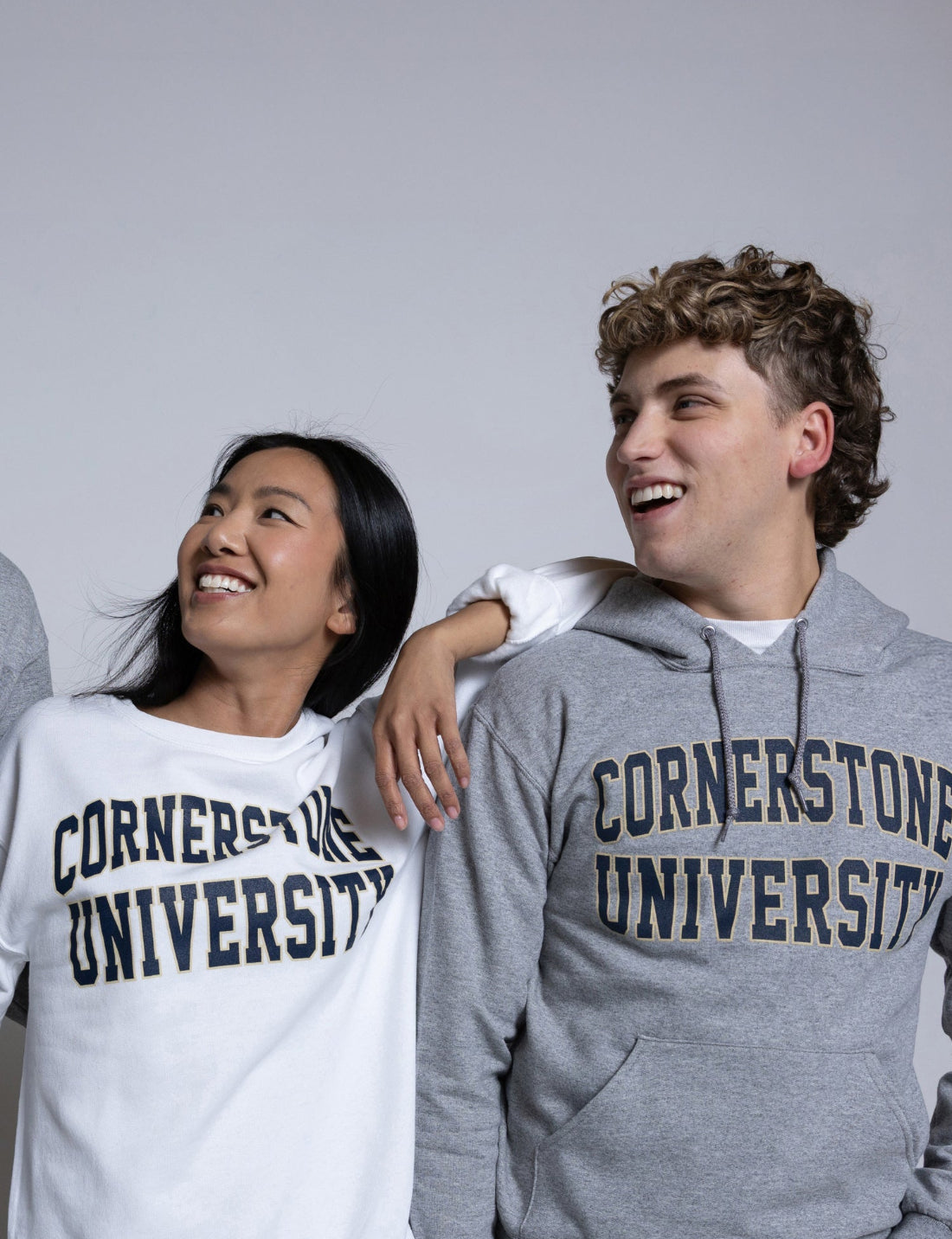 Two people wearing 'Cornerstone University' sweatshirts against a plain background