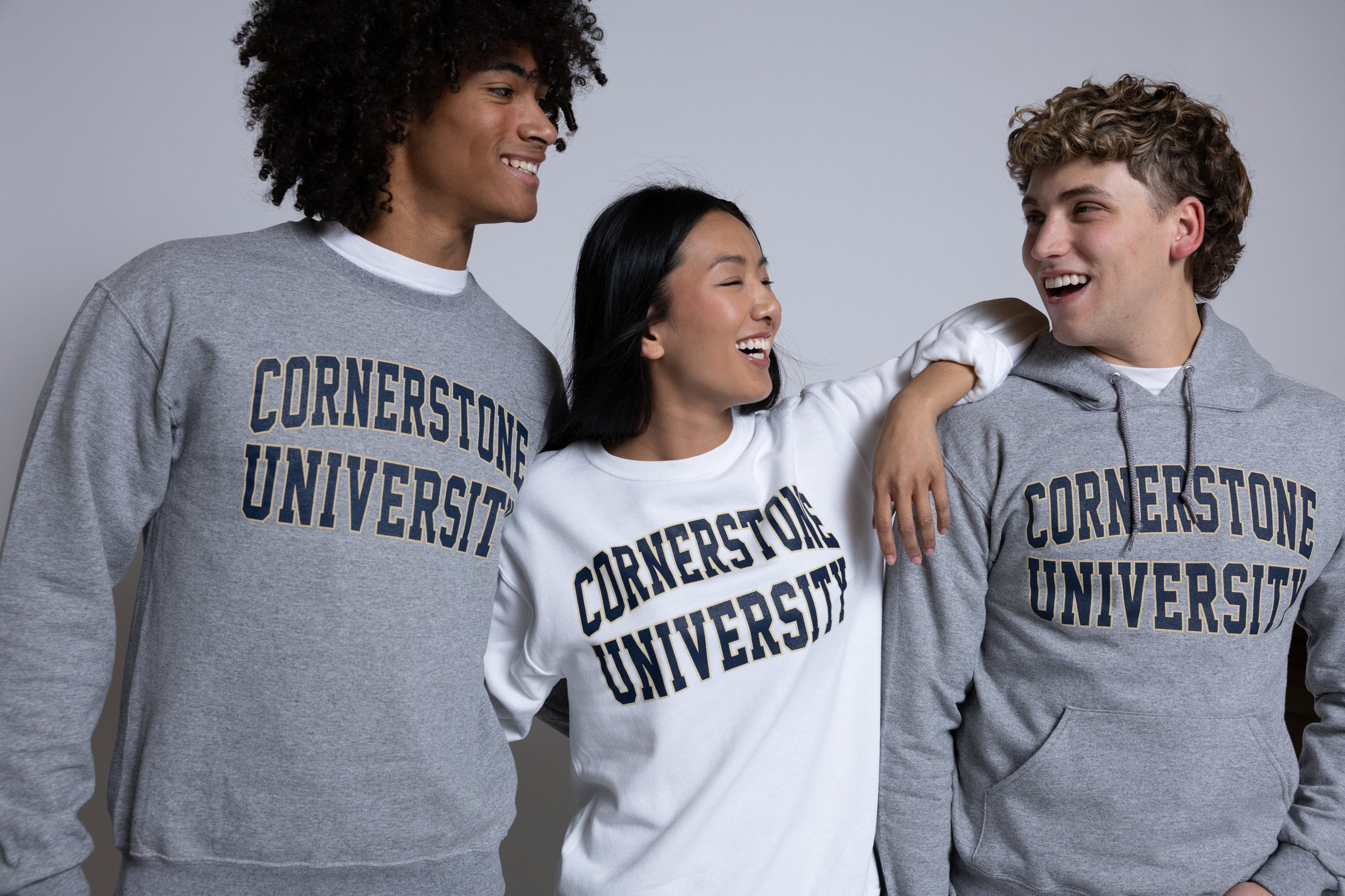 Three people wearing 'Cornerstone University' sweatshirts against a plain background