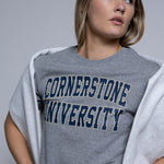Person wearing a gray 'Cornerstone University' t-shirt against a plain background