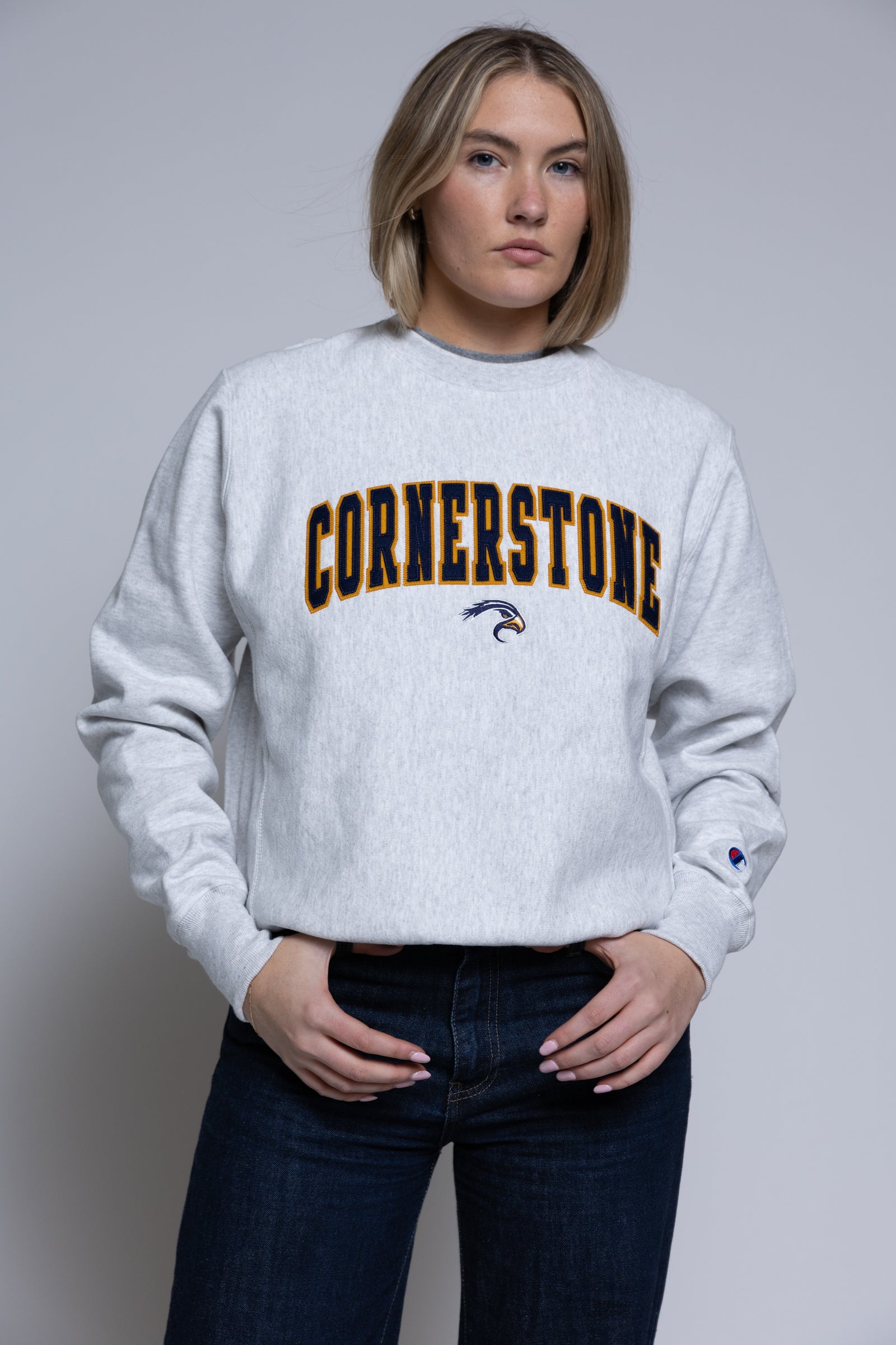 Person wearing a light crewneck sweatshirt with 'Cornerstone' on it