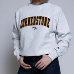 Person wearing a light crewneck sweatshirt with 'Cornerstone' on it