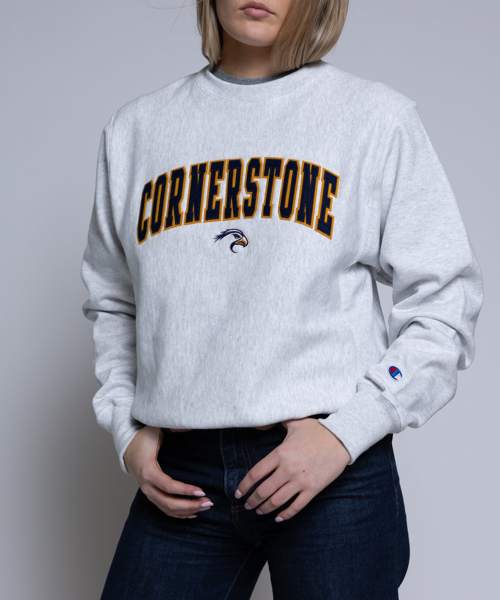 Person wearing a light crewneck sweatshirt with 'Cornerstone' on it