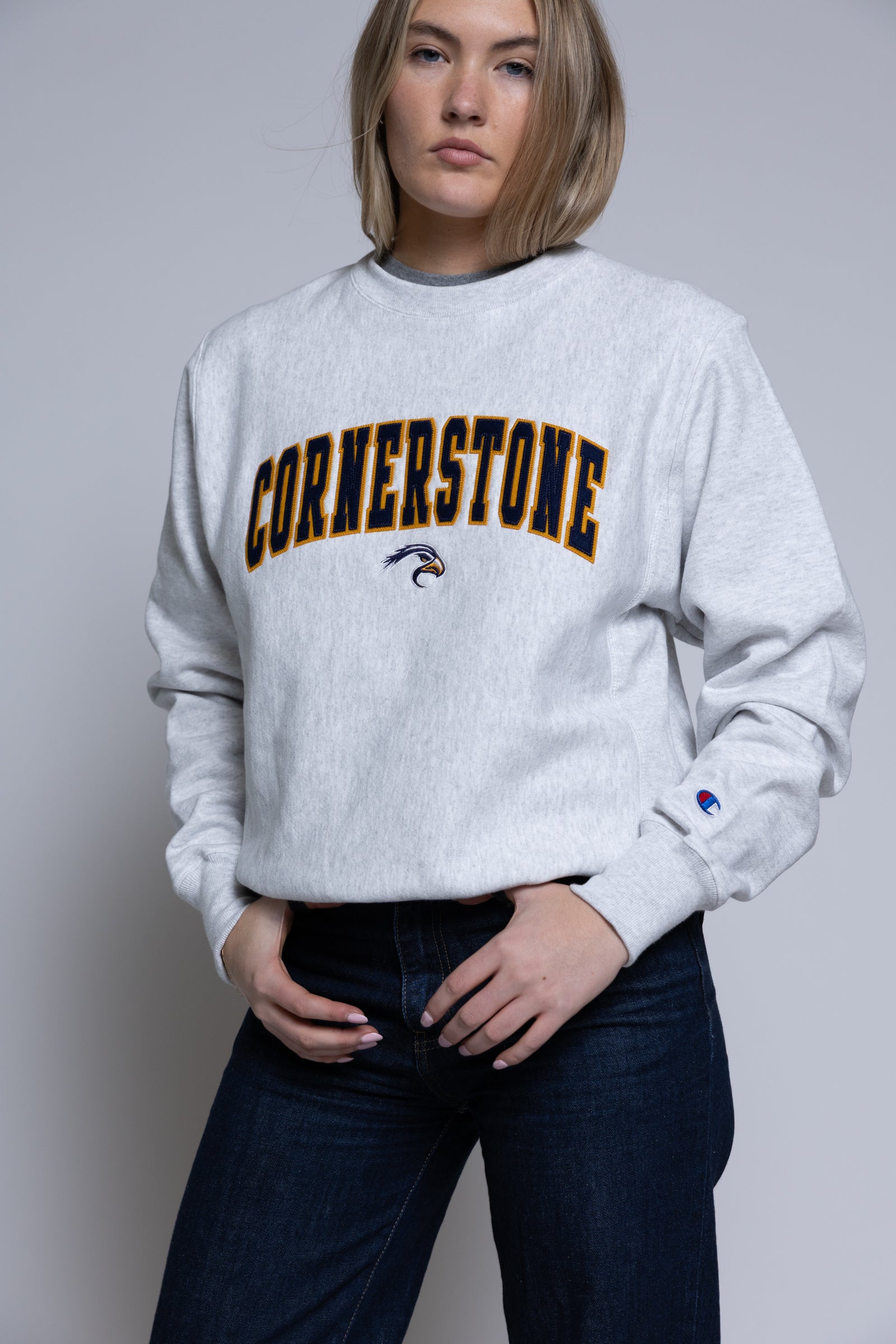 Person wearing a light crewneck sweatshirt with 'Cornerstone' on it