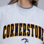 Person wearing a light crewneck sweatshirt with 'Cornerstone' on it