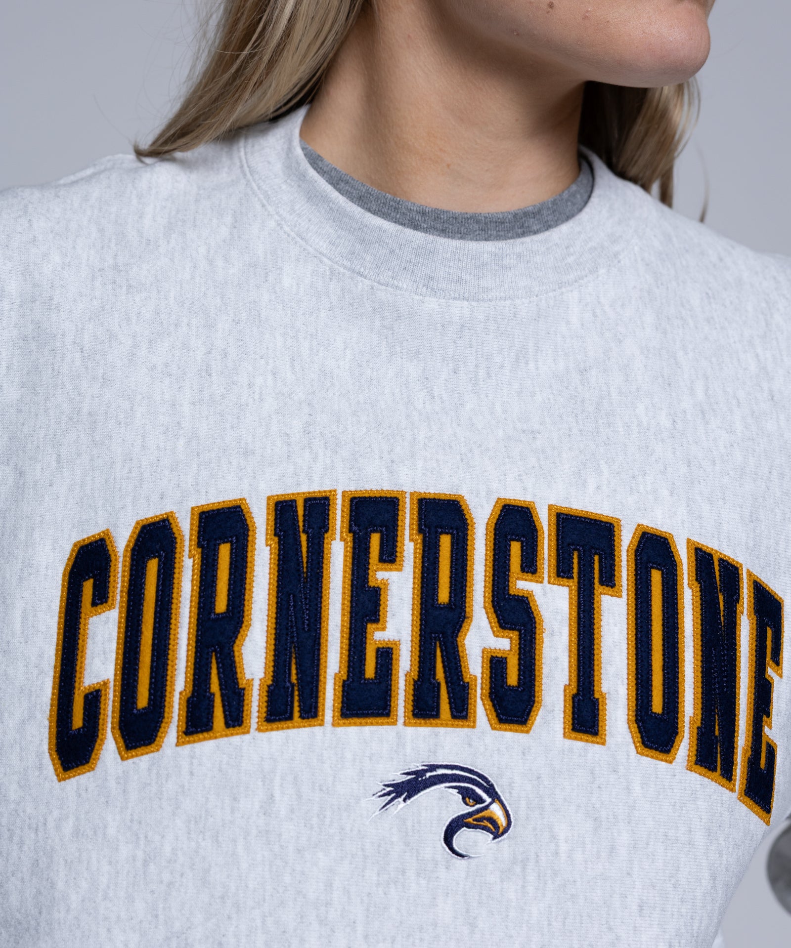 Person wearing a light crewneck sweatshirt with 'Cornerstone' on it