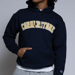 Person wearing a navy hoodie with 'Cornerstone' text on a plain background