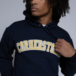 Person wearing a navy hoodie with 'Cornerstone' text on a plain background