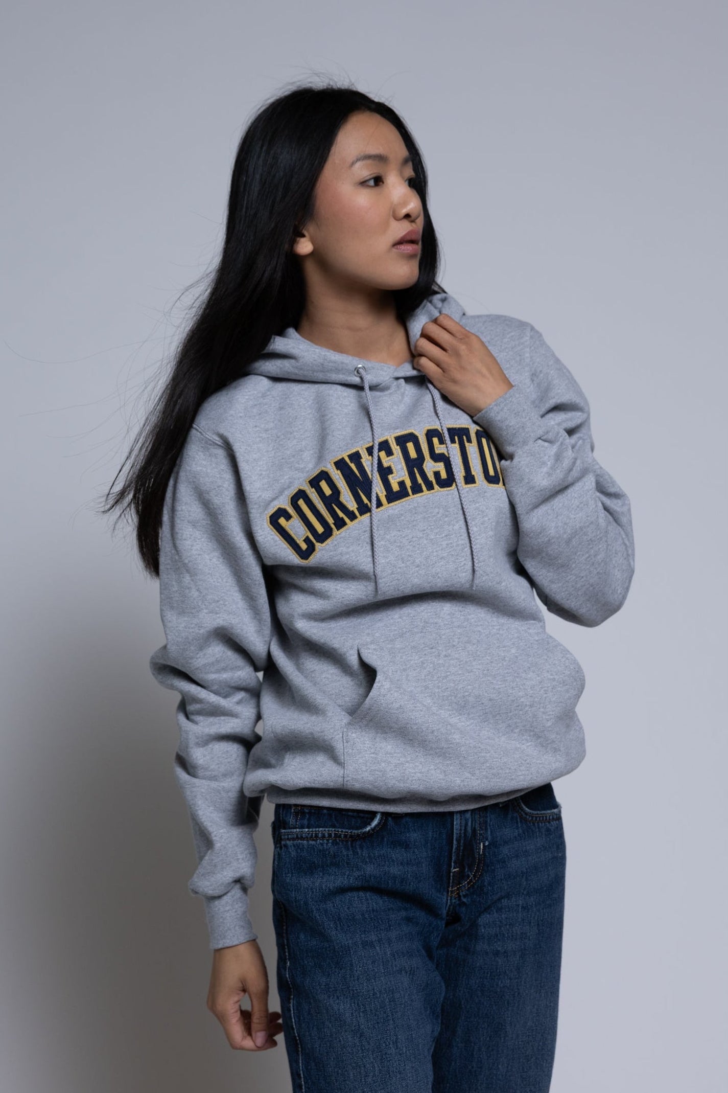 Woman wearing a gray hoodie with 'Cornerstone' text on a plain background