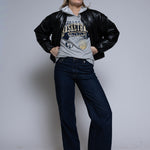 Person wearing a black leather jacket over a gray hoodie with Cornerstone basketball graphics on a plain background