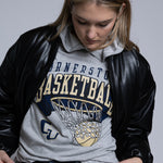 Person wearing a black leather jacket over a gray hoodie with Cornerstone basketball graphics on a plain background