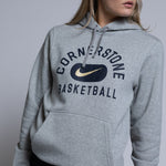 Person wearing a gray hoodie with 'Cornerstone Basketball' and Nike logo on a plain background