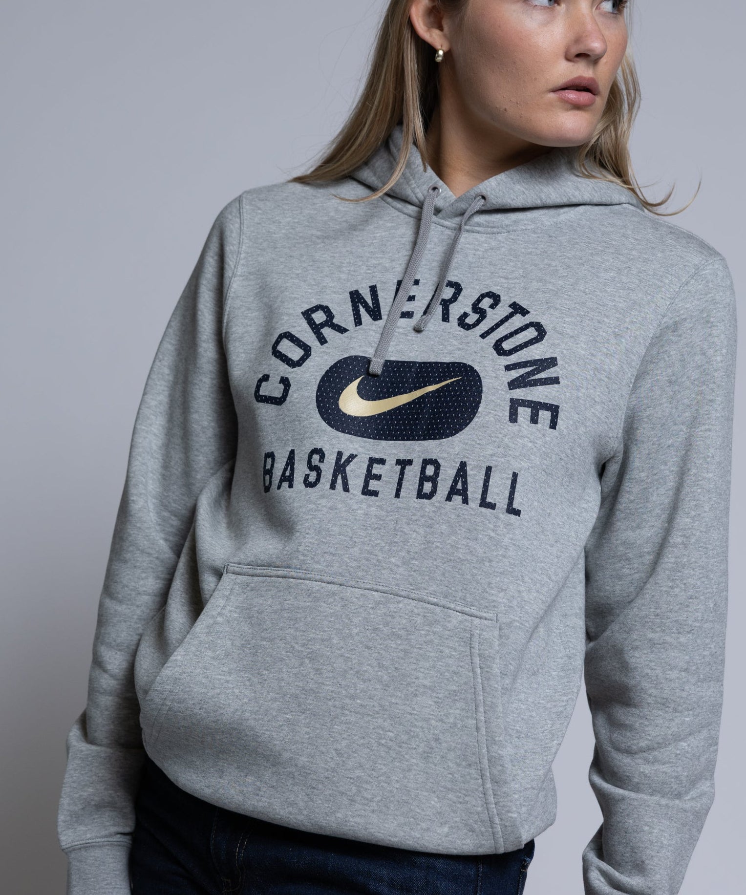 Person wearing a gray hoodie with 'Cornerstone Basketball' and Nike logo on a plain background