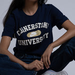 Person wearing a navy blue t-shirt with 'Cornerstone University' text, sitting on a light background
