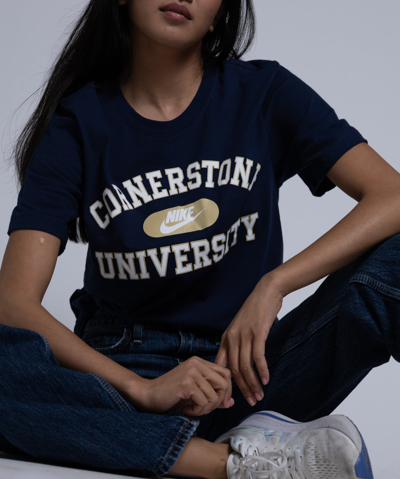 Person wearing a navy blue t-shirt with 'Cornerstone University' text, sitting on a light background