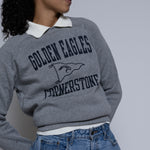 Person wearing a gray crewneck sweatshirt with 'Golden Eagles Cornerstone' text and design.