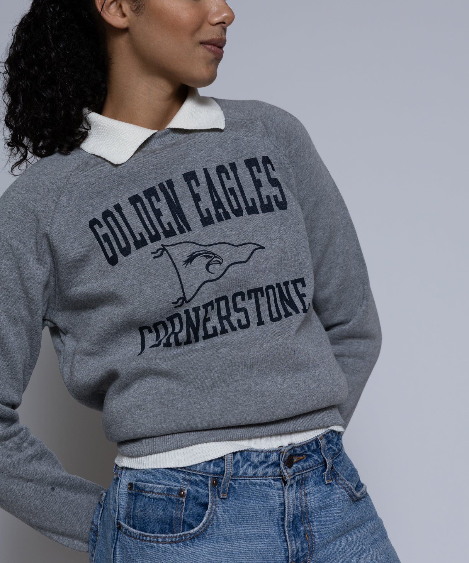 Person wearing a gray crewneck sweatshirt with 'Golden Eagles Cornerstone' text and design.