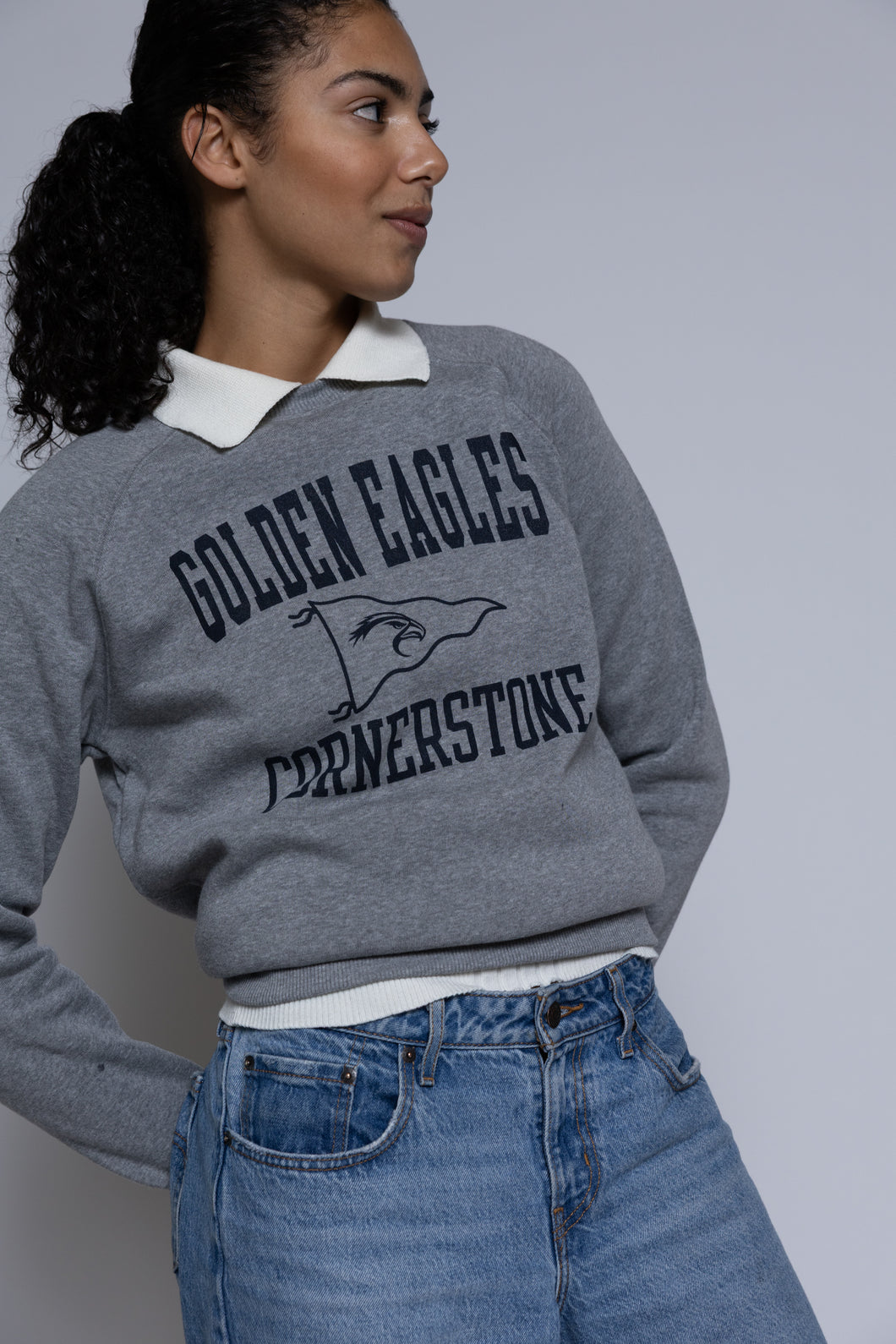 Person wearing a gray crewneck sweatshirt with 'Golden Eagles Cornerstone' text and design.