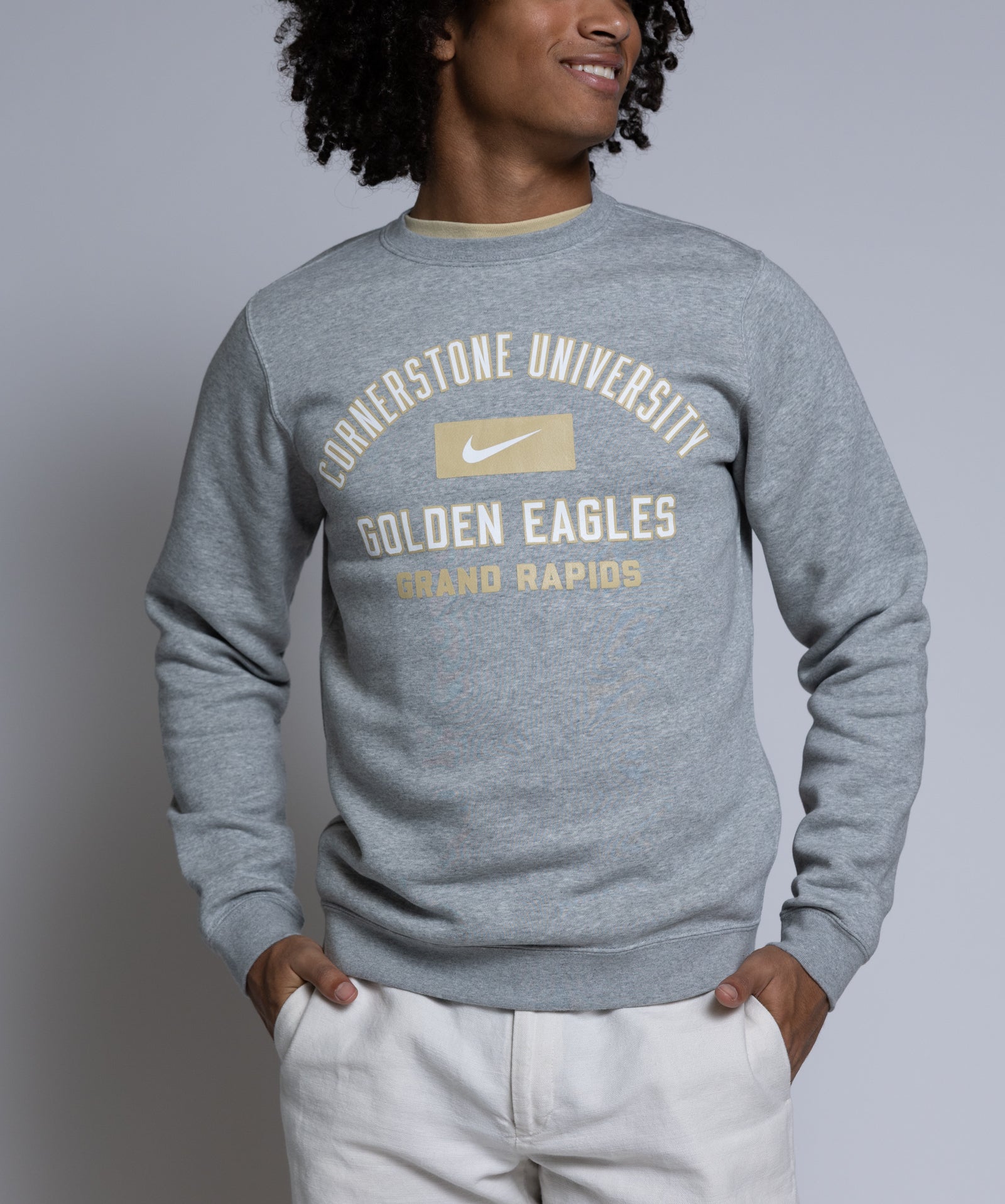 Person wearing a gray sweatshirt with 'Cornerstone University Golden Eagles Grand Rapids' text on a plain background