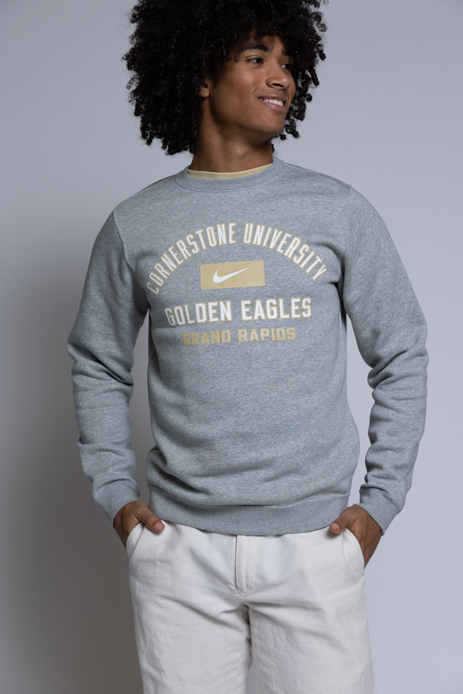 Person wearing a gray sweatshirt with 'Cornerstone University Golden Eagles Grand Rapids' text on a plain background