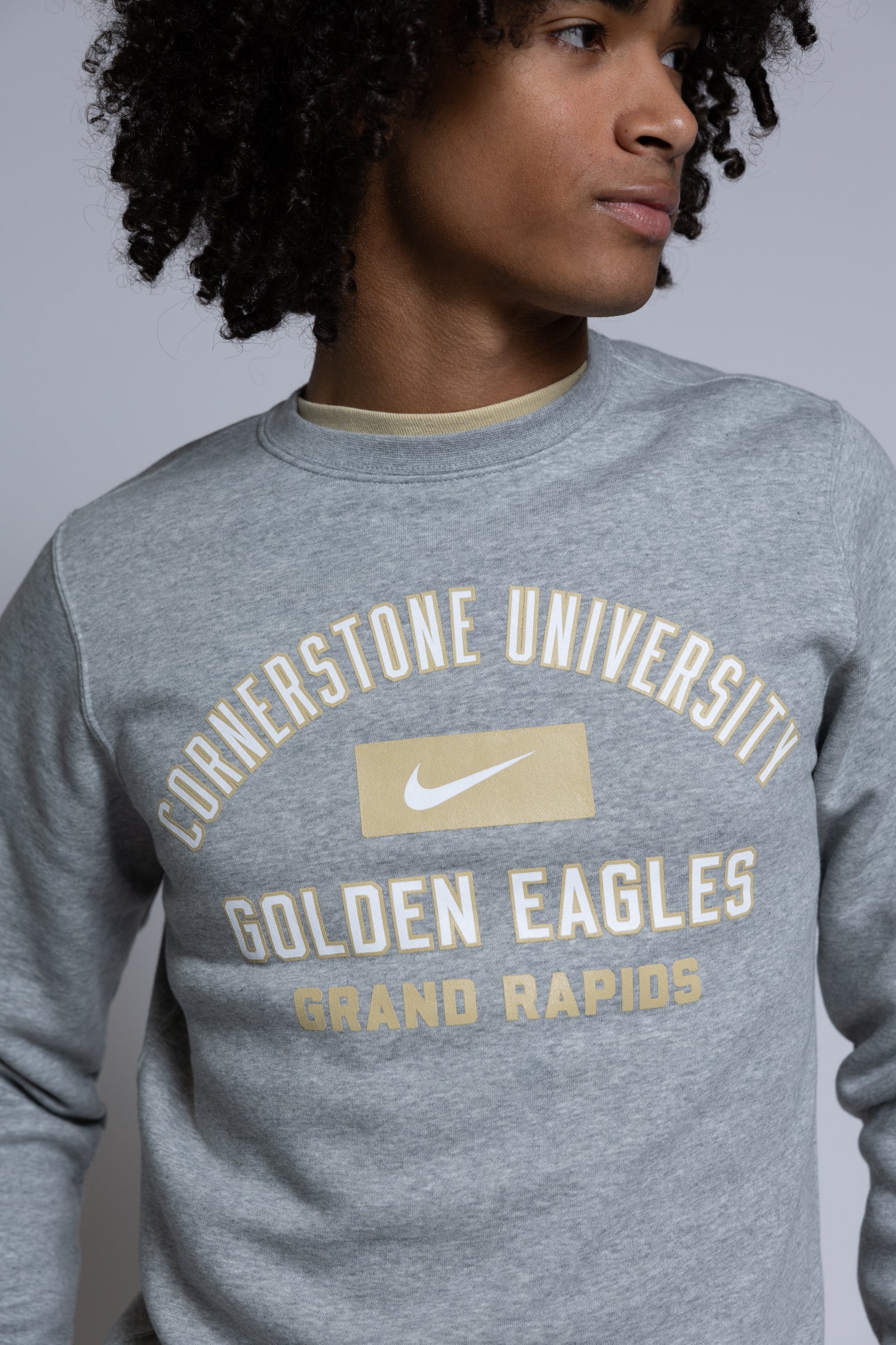 Person wearing a gray sweatshirt with 'Cornerstone University Golden Eagles Grand Rapids' text on a plain background